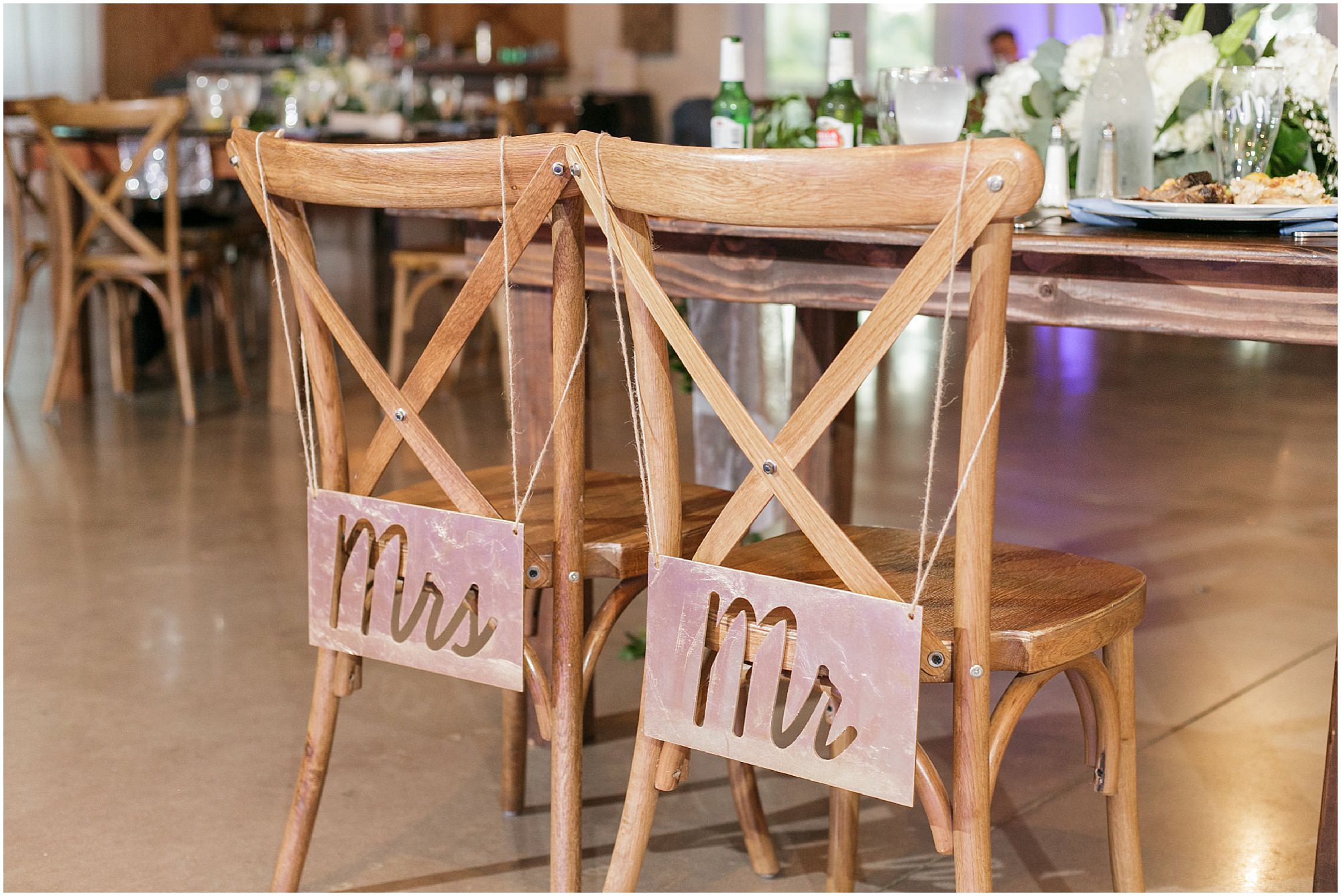 Stencils from iron sheets saying "Mr" and "Mrs" hanging on the back of the bride and groom's chairs. 