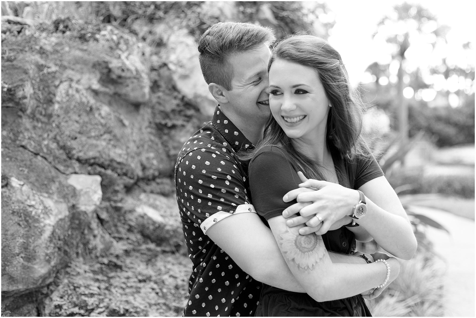 Black and white photo of a guy hugging his fiancé. 
