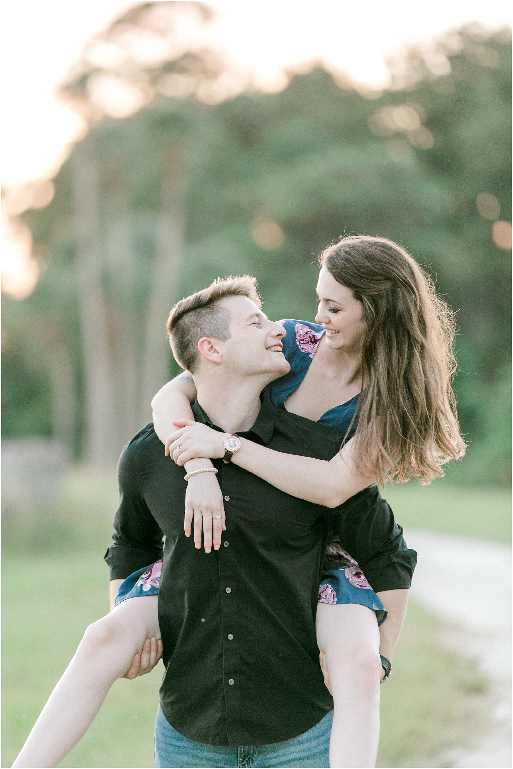 Guy giving his fiancé a piggyback ride as they walk around outdoors. 