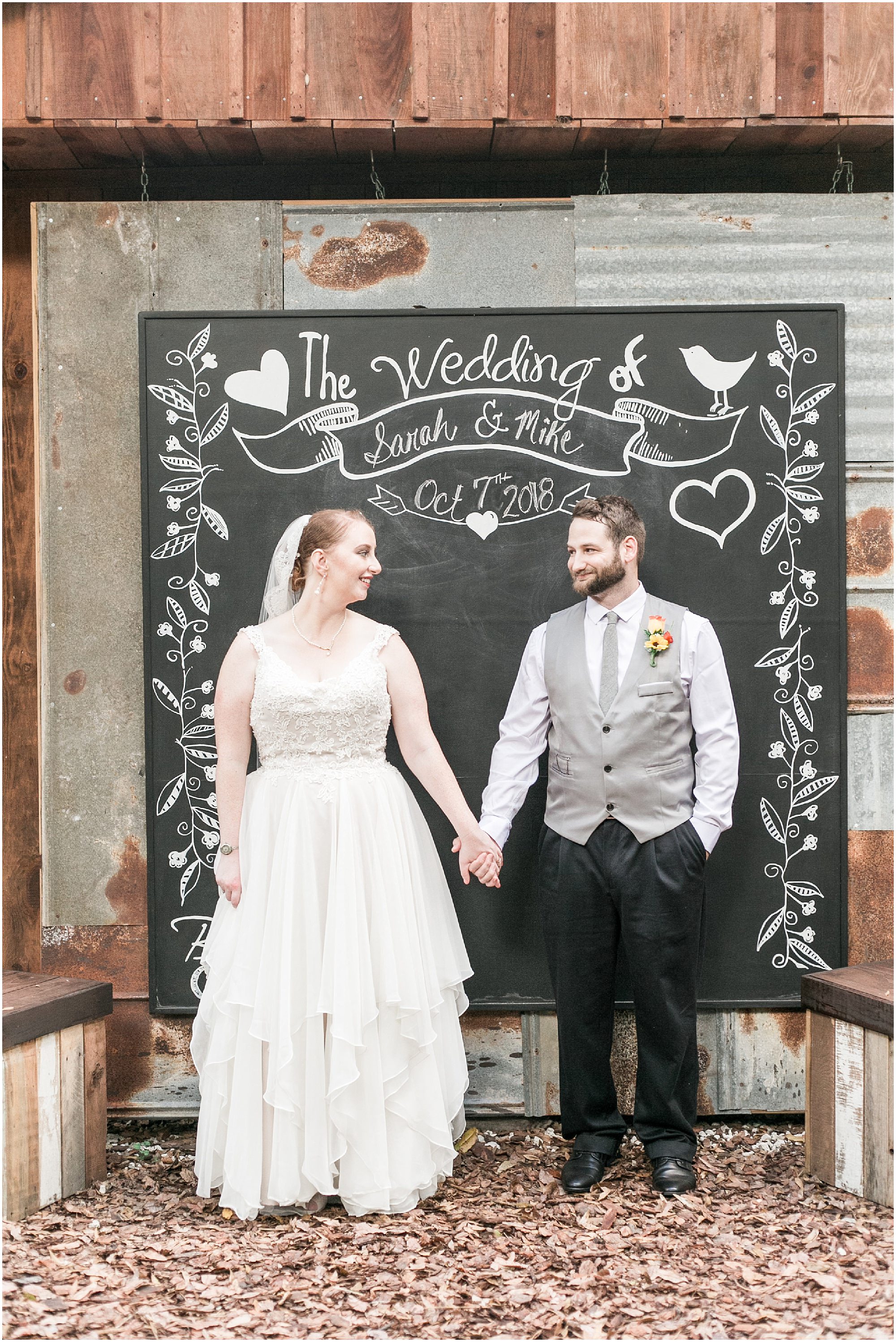 Bride and groom taking a photo in front of a chalkboard 