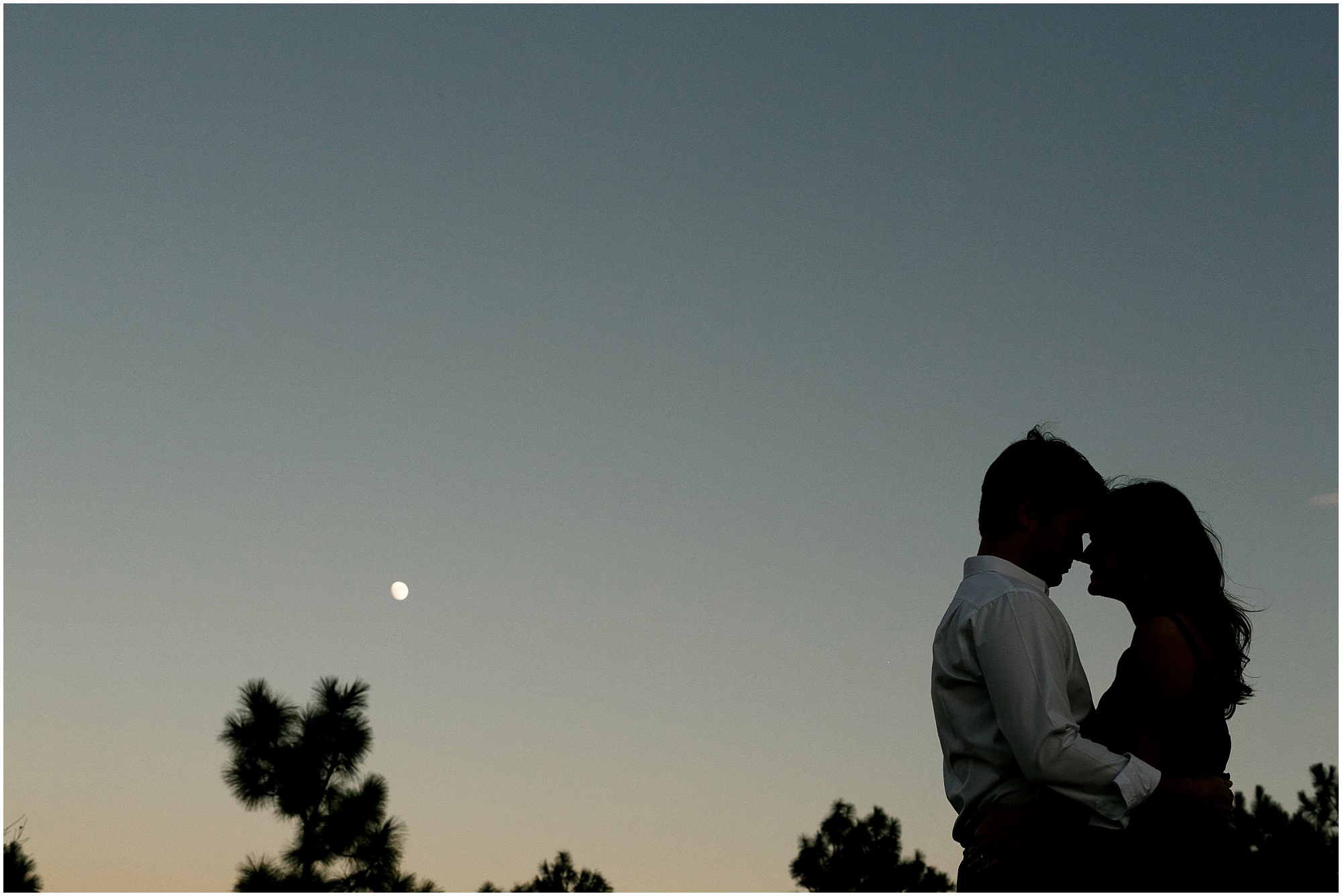 Sunny autumn engagement session comes to an end with the couple hugging with the moon in the background. 