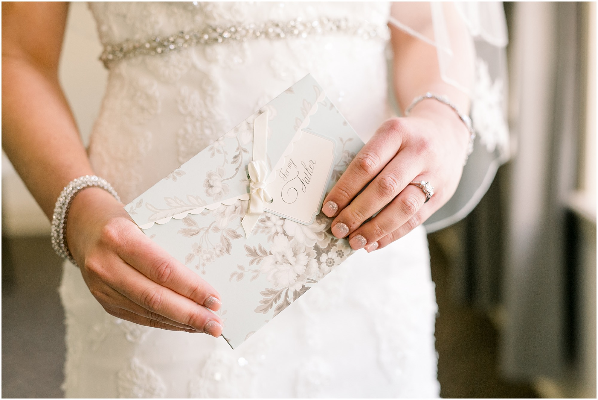Bride holding a card to give to her father before they do a first look.