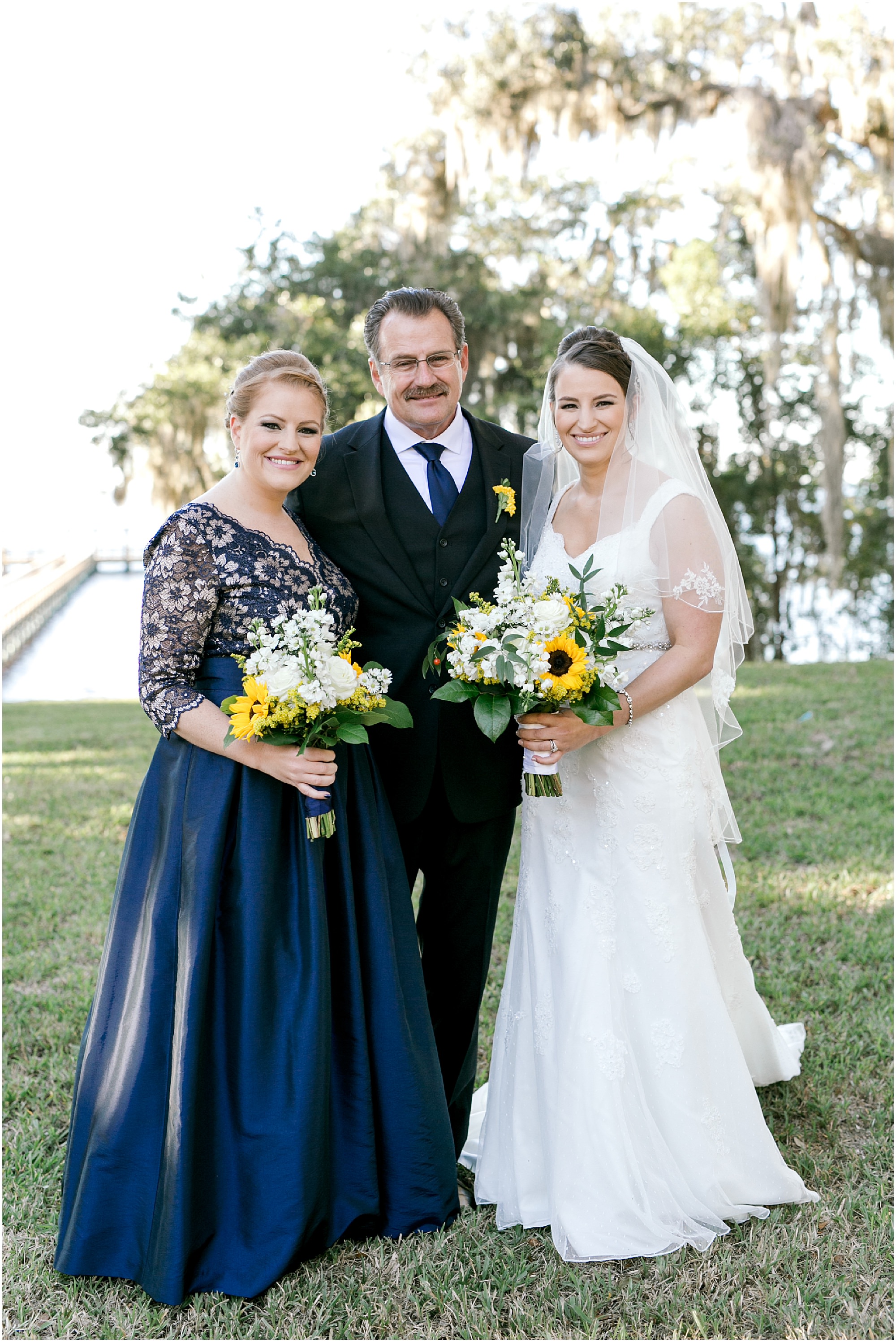 Bride takes a photos with her sister and her dad
