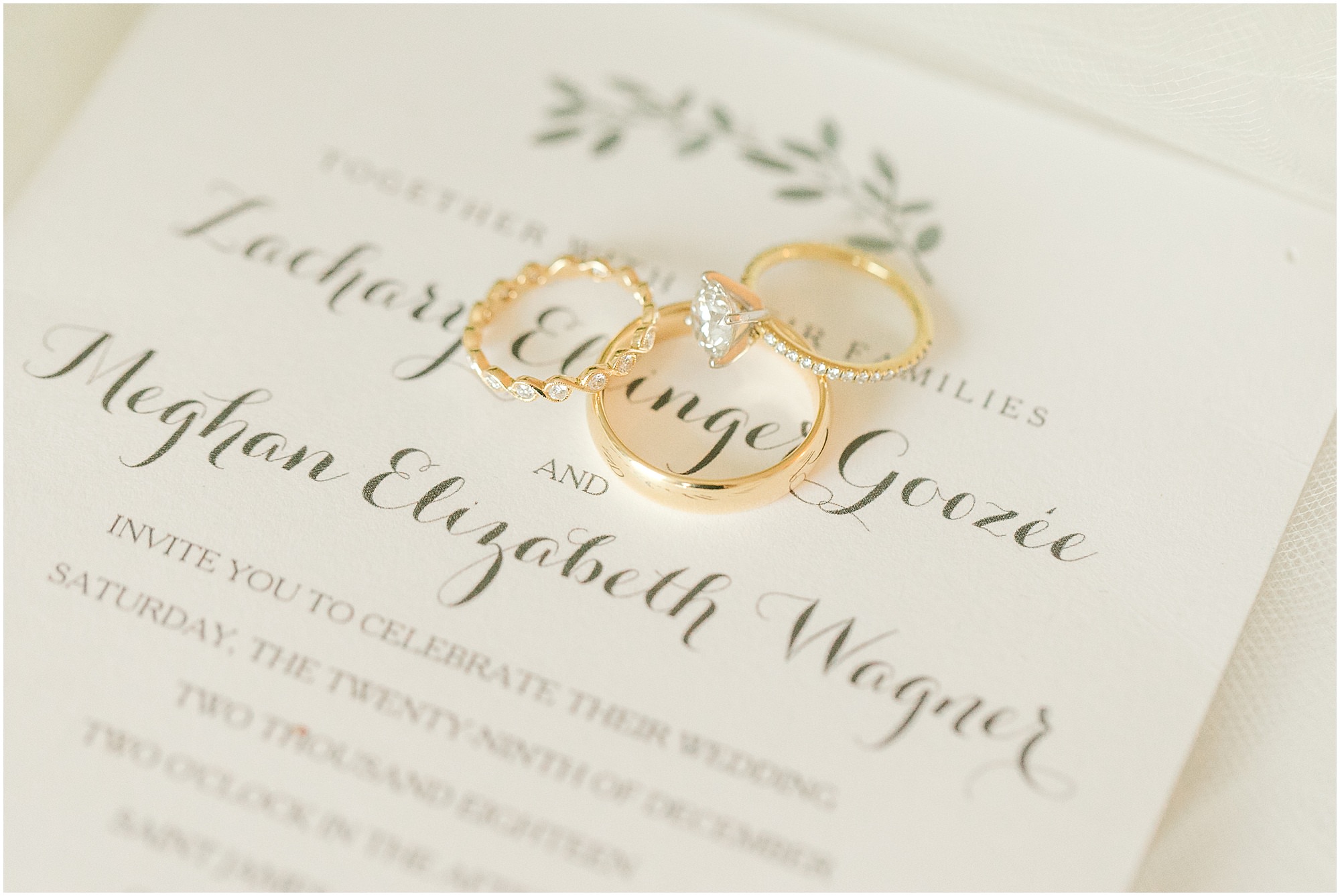Elegant Vintage Wedding invitation with gold wedding rings laying on top of it. 