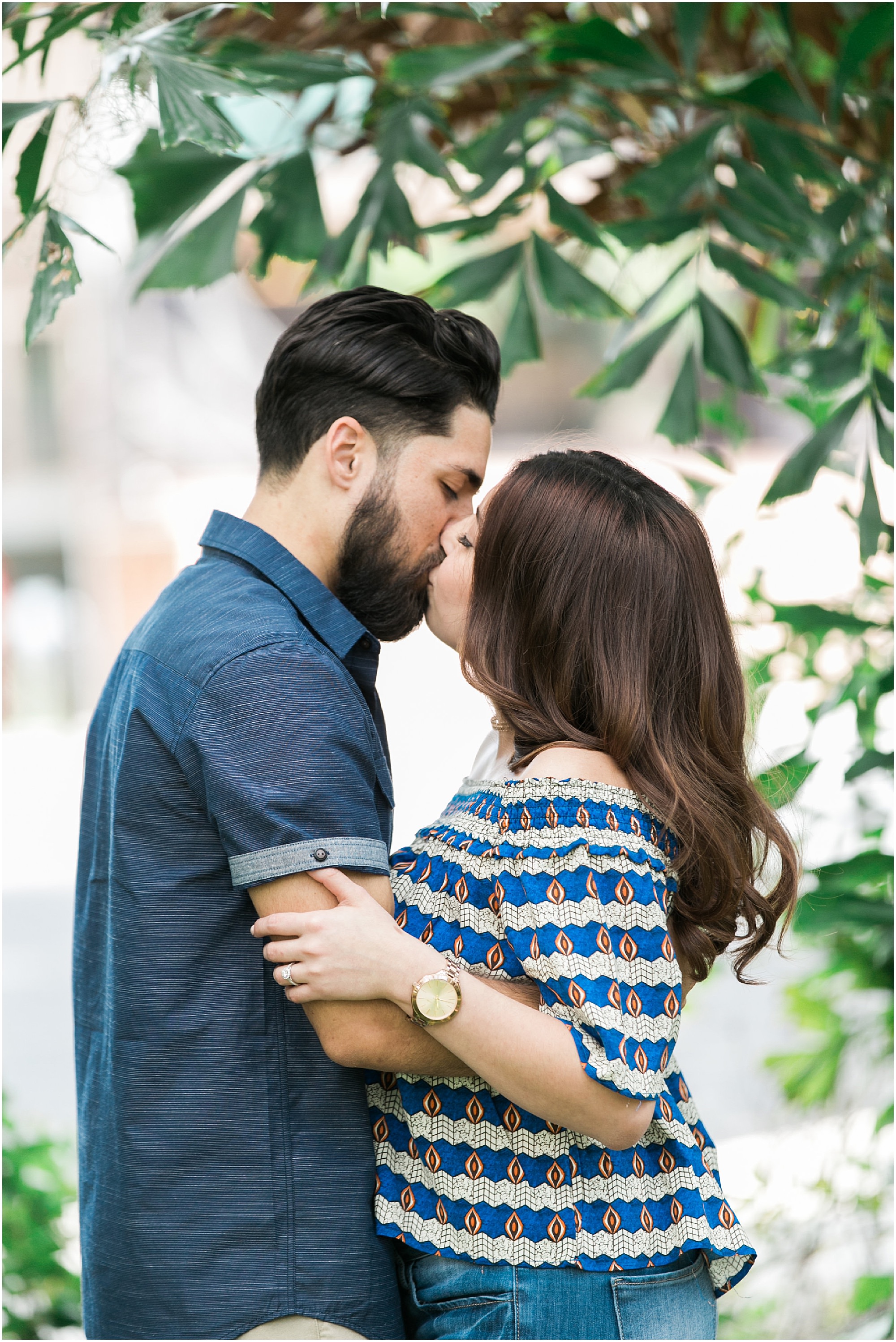 Engagement Session Tips will help you have the shoot you have been dreaming of. Engaged couple kisses in colorful casual clothes under a green tree