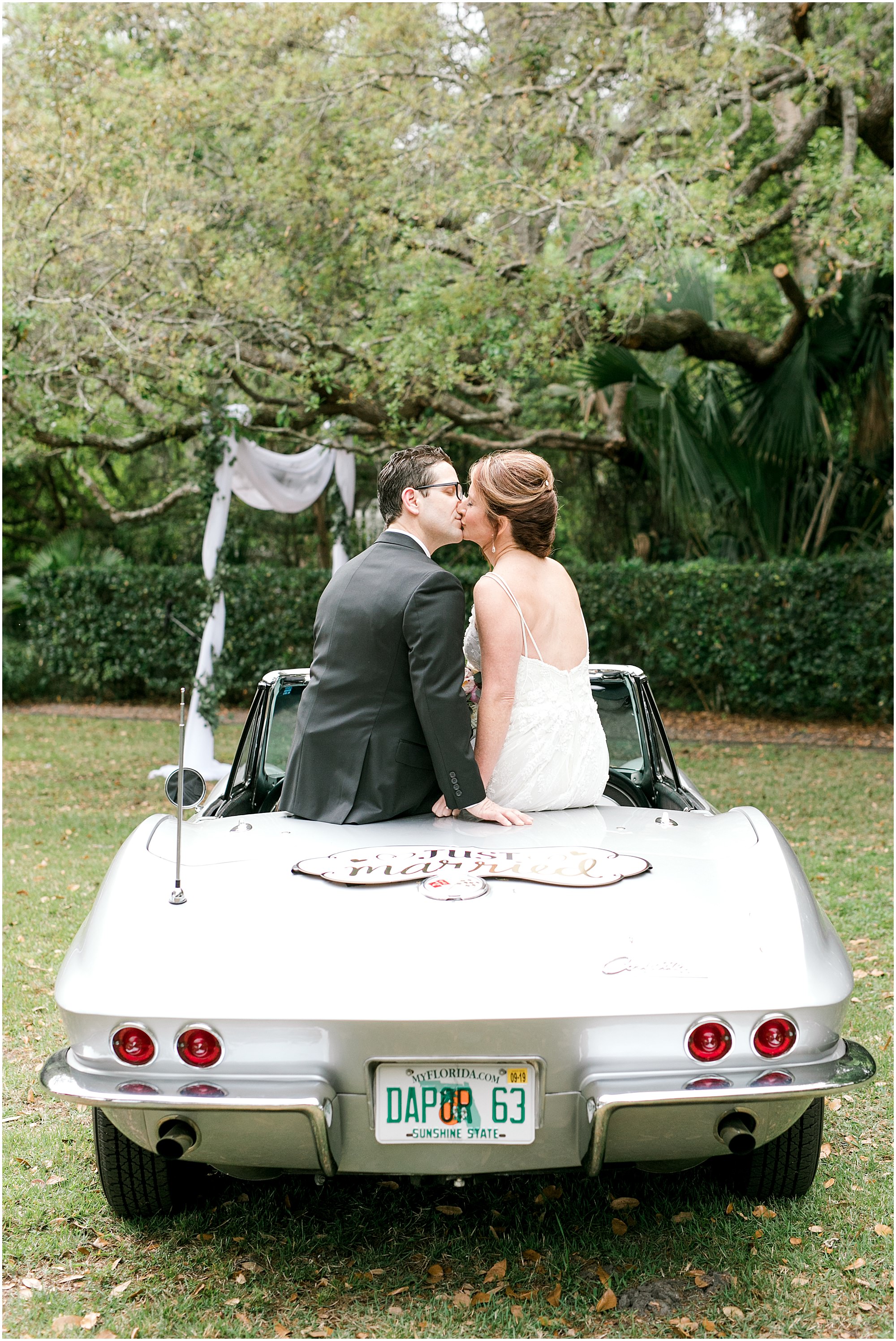 Family Estate Wedding bride and groom kissing while sitting in the back of an antique Corvette