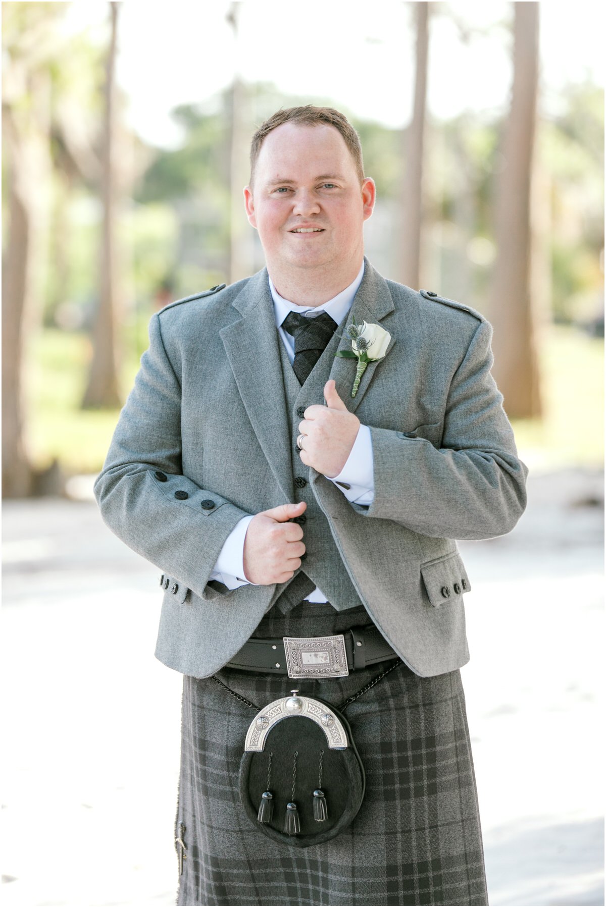 Groom in traditional Scottish wear standing on the shoreline