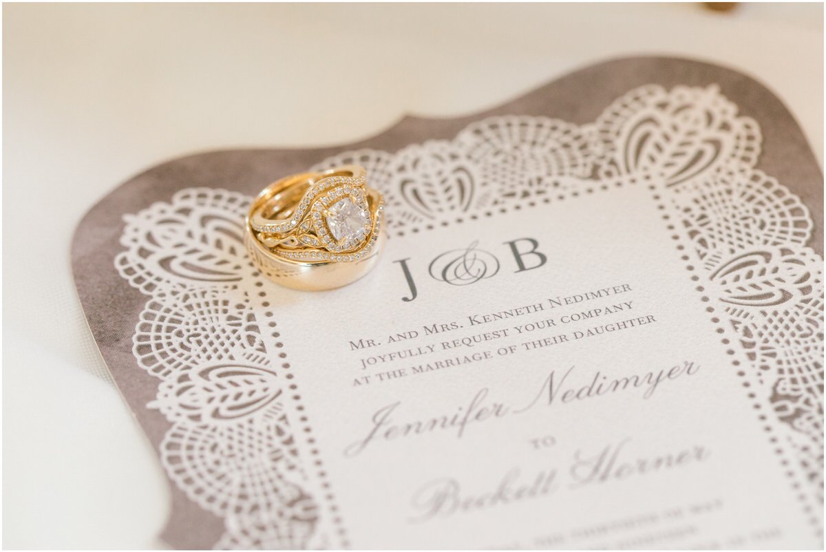 Gold wedding rings on top of invitations for elegantly intimate Howey Mansion wedding