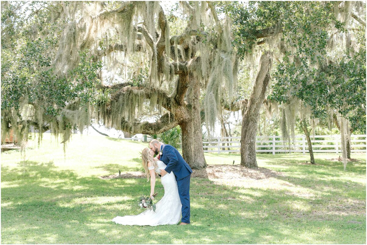 bride and groom kissing under oak trees