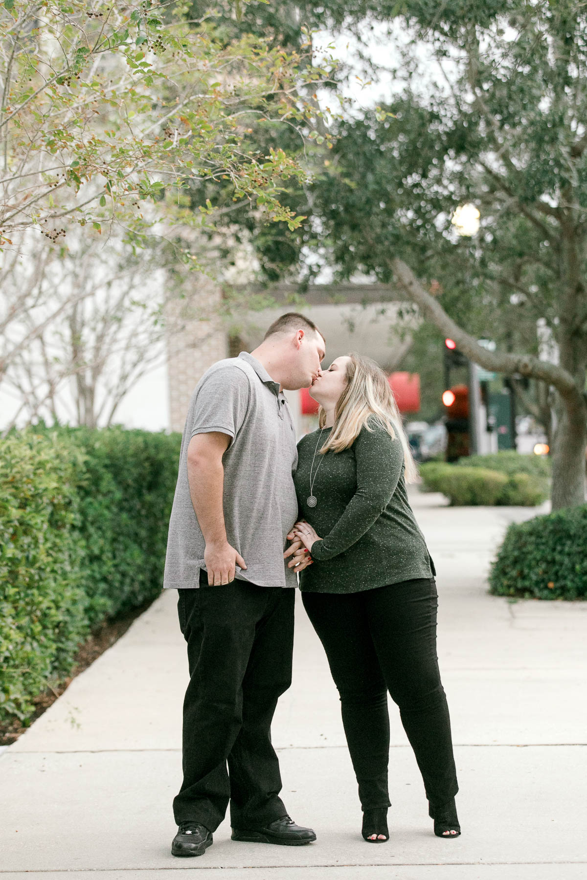 Couple kiss on the side walk of historic downtown Sanford at engagement session.