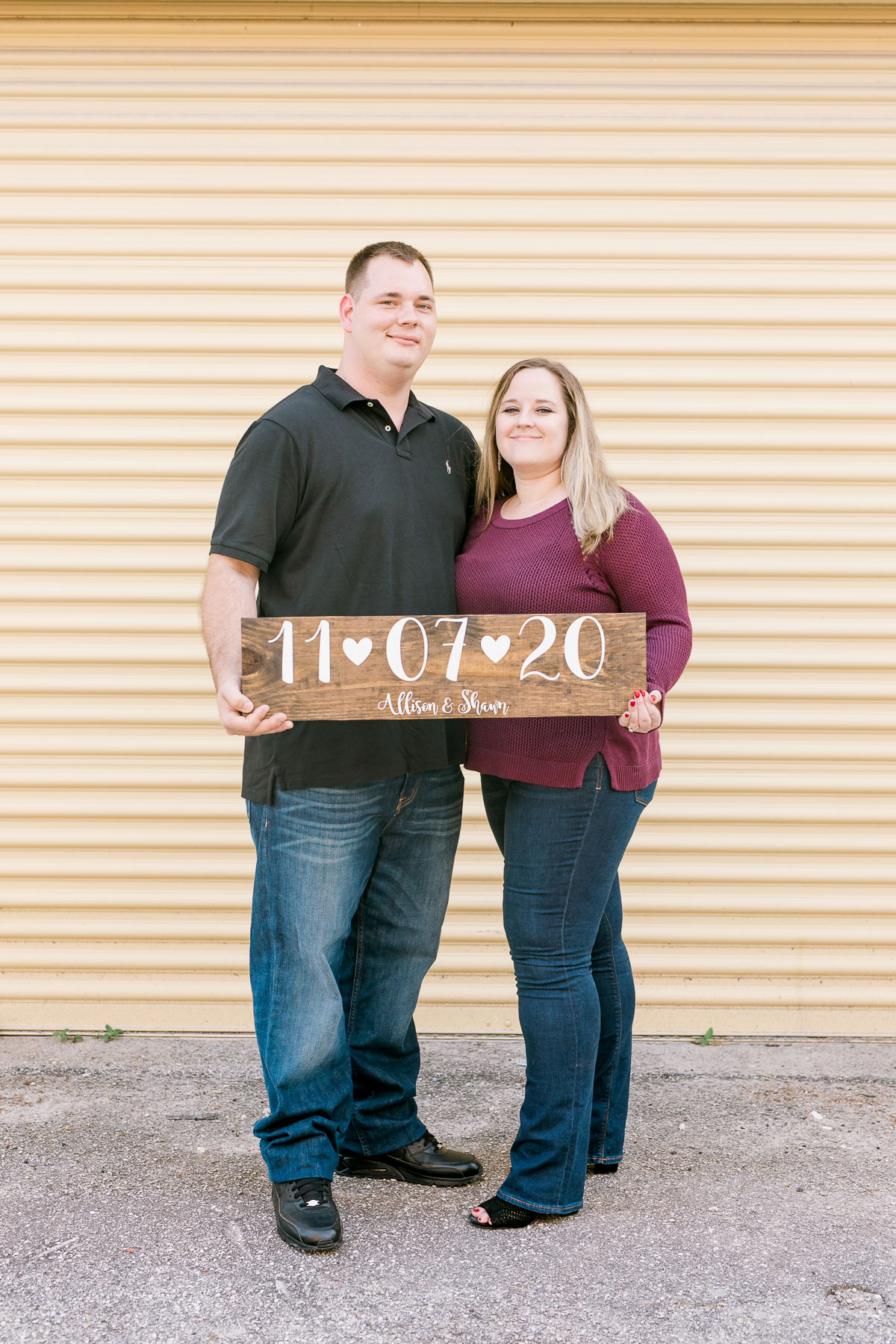 Couple holding a wood sign with their wedding date on it