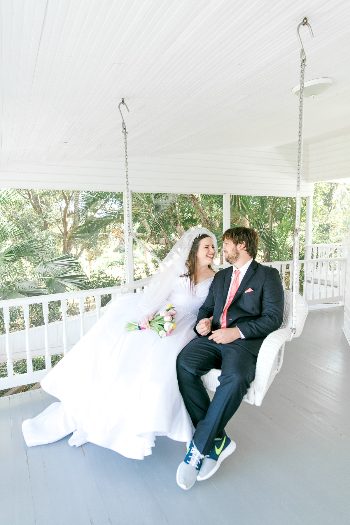 bride and groom sitting on a porch swing