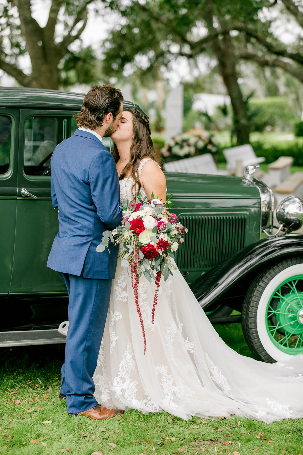 Bride and groom share a kiss next to antique truck