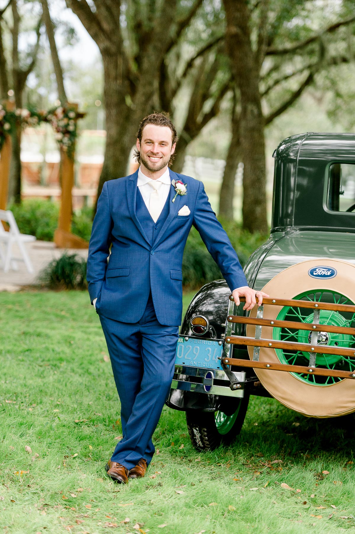 groom posing next to green vintage truck