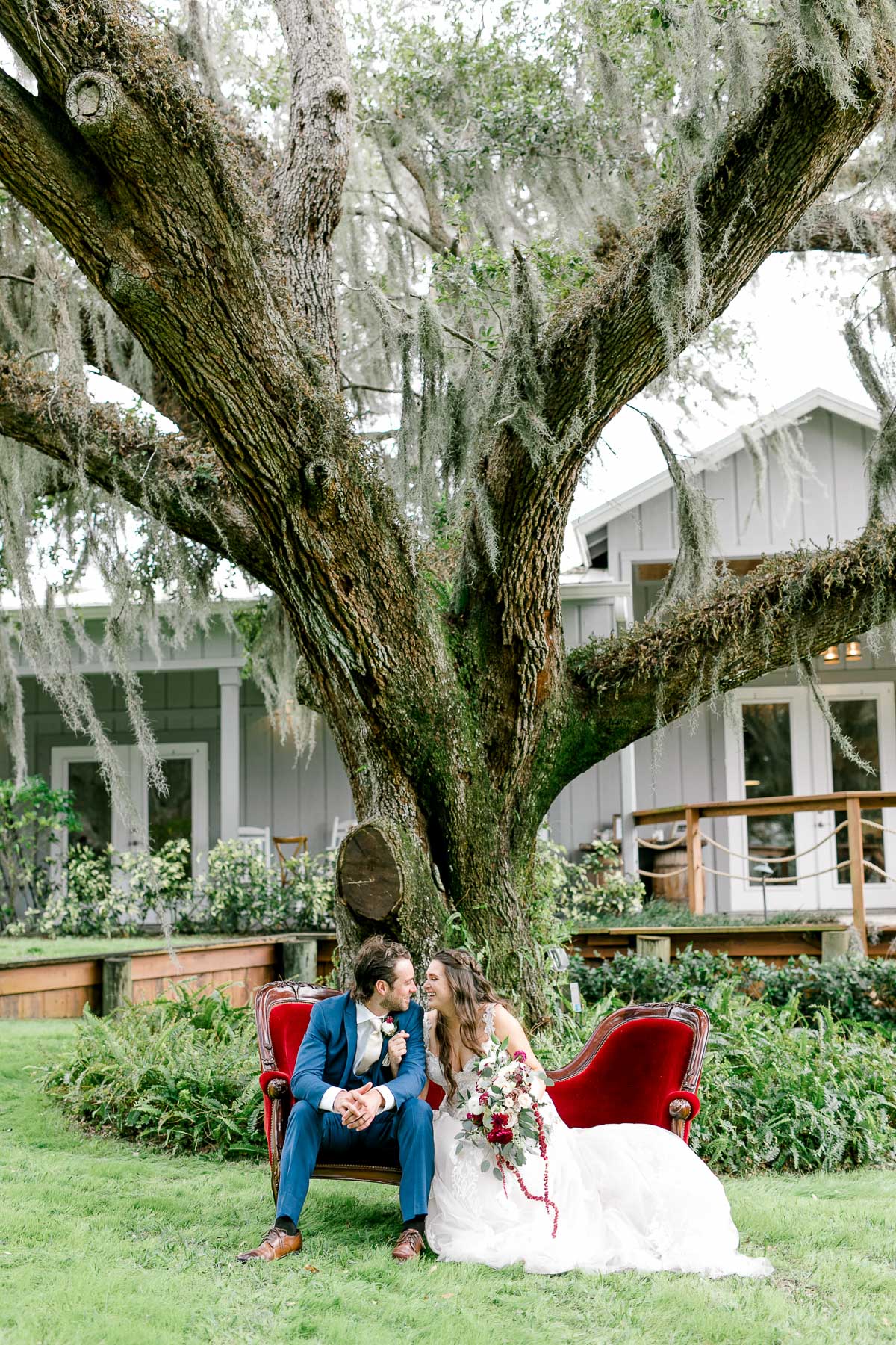 Bride and groom sitting on couch under old oak trees