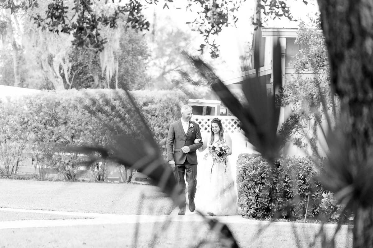 Black and white photo of dad and bride walking to wedding ceremony