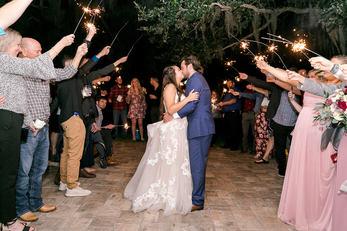 bride and groom kiss under sparklers leaving their farm wedding