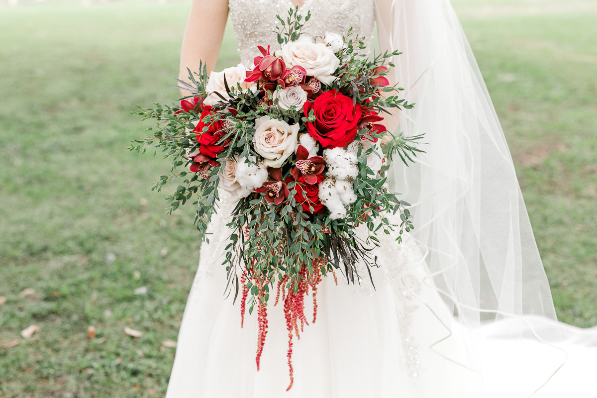 Close up of bride holding shades of red bouquet