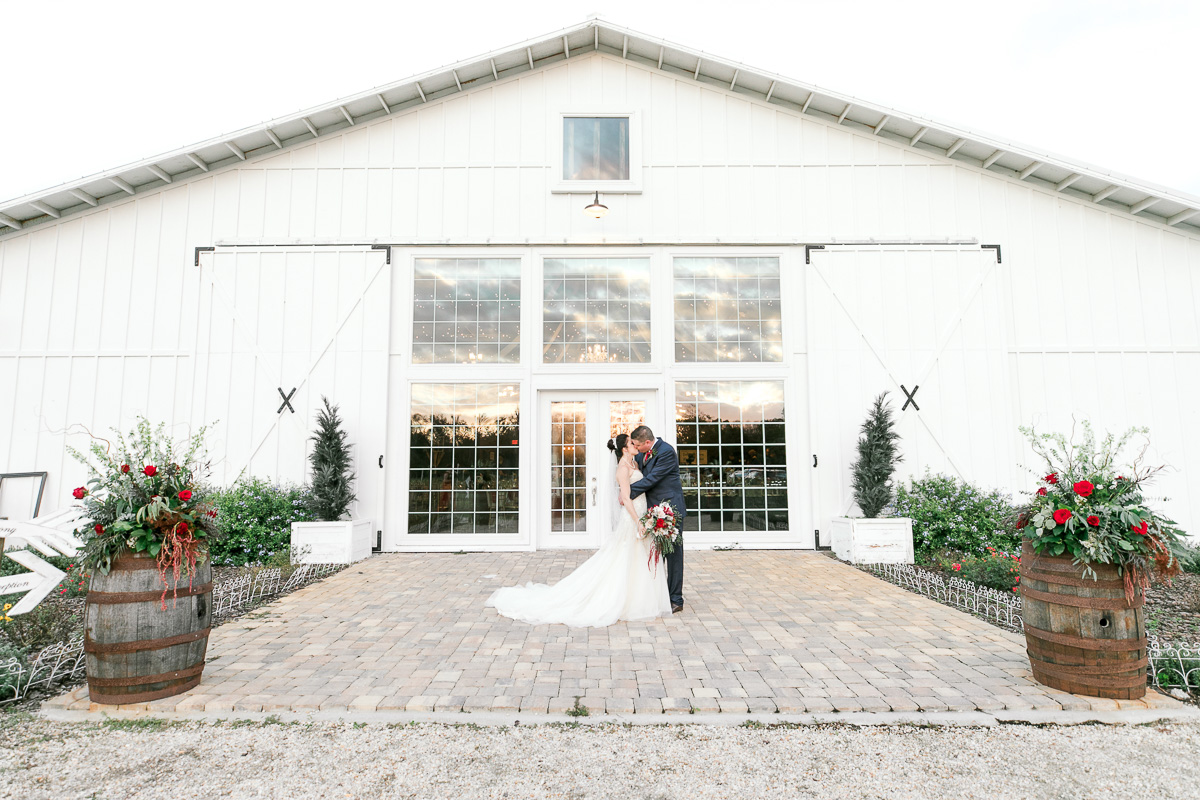Bride and groom kiss outside of white barn