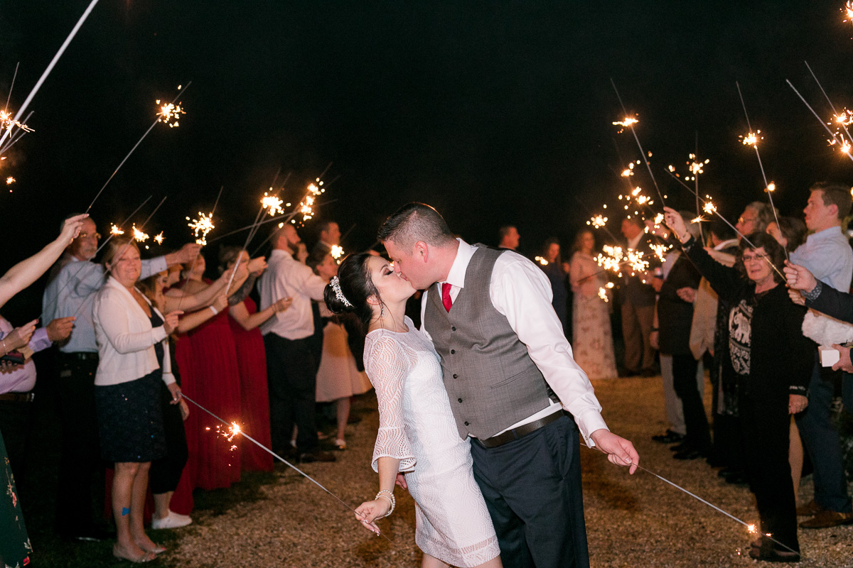 Bride and groom kiss at the end of the sparkler grand exit from romantic Ever After Farms wedding. 
