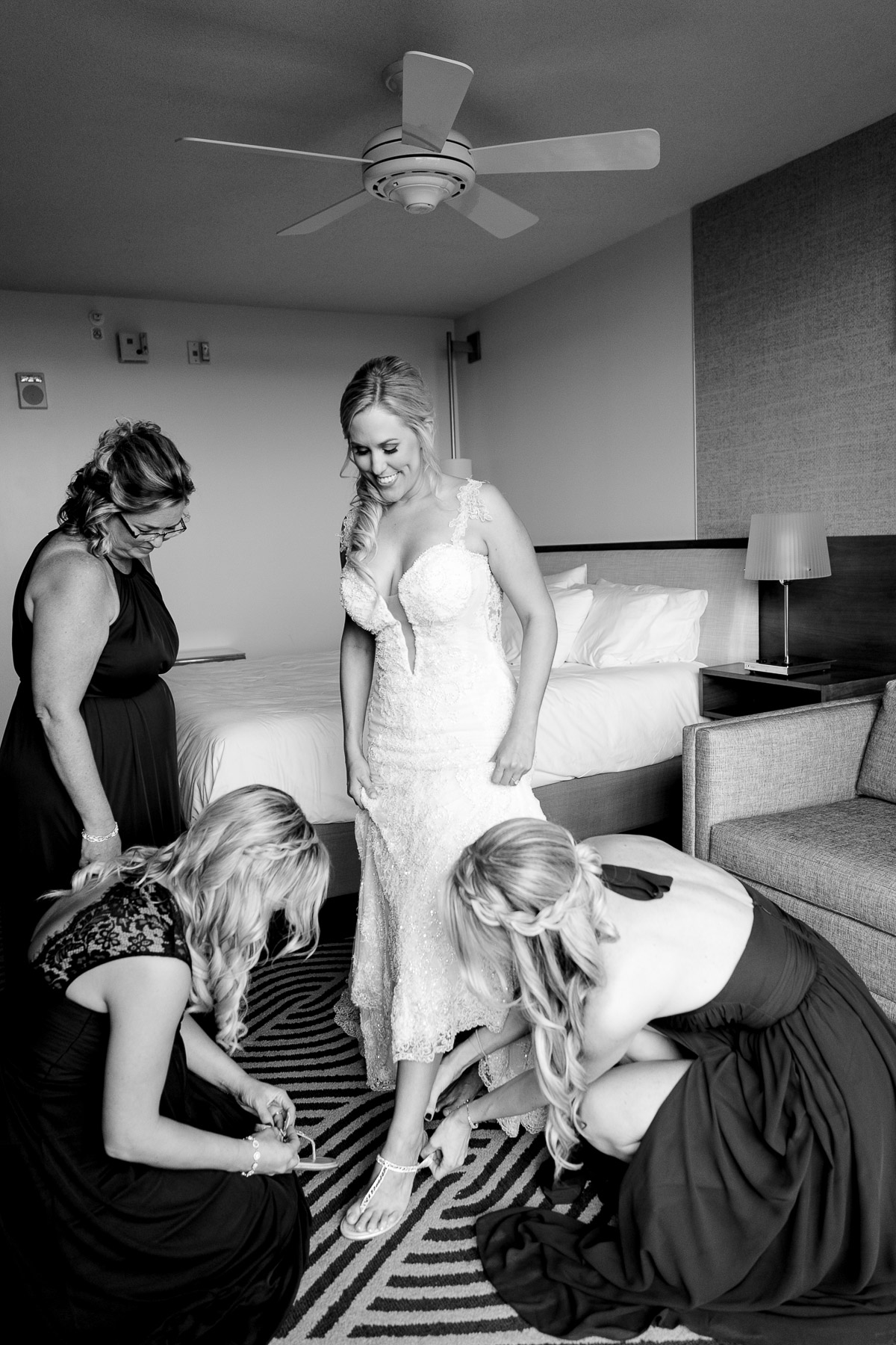 Bridesmaids helping bride put on her shoes