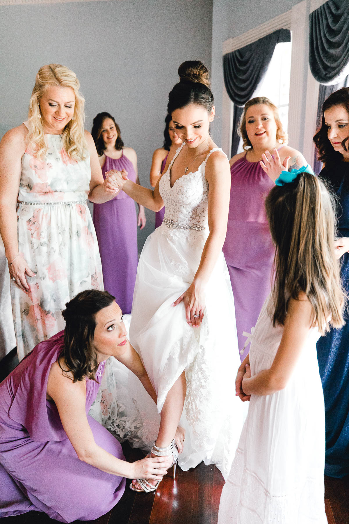 Bridesmaids helping bride put on her wedding shoes
