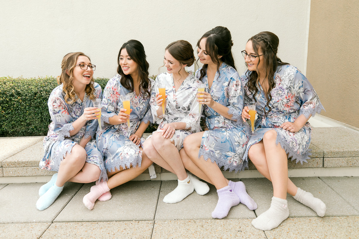 bride and bridesmaids hanging out in matching floral robes before wedding