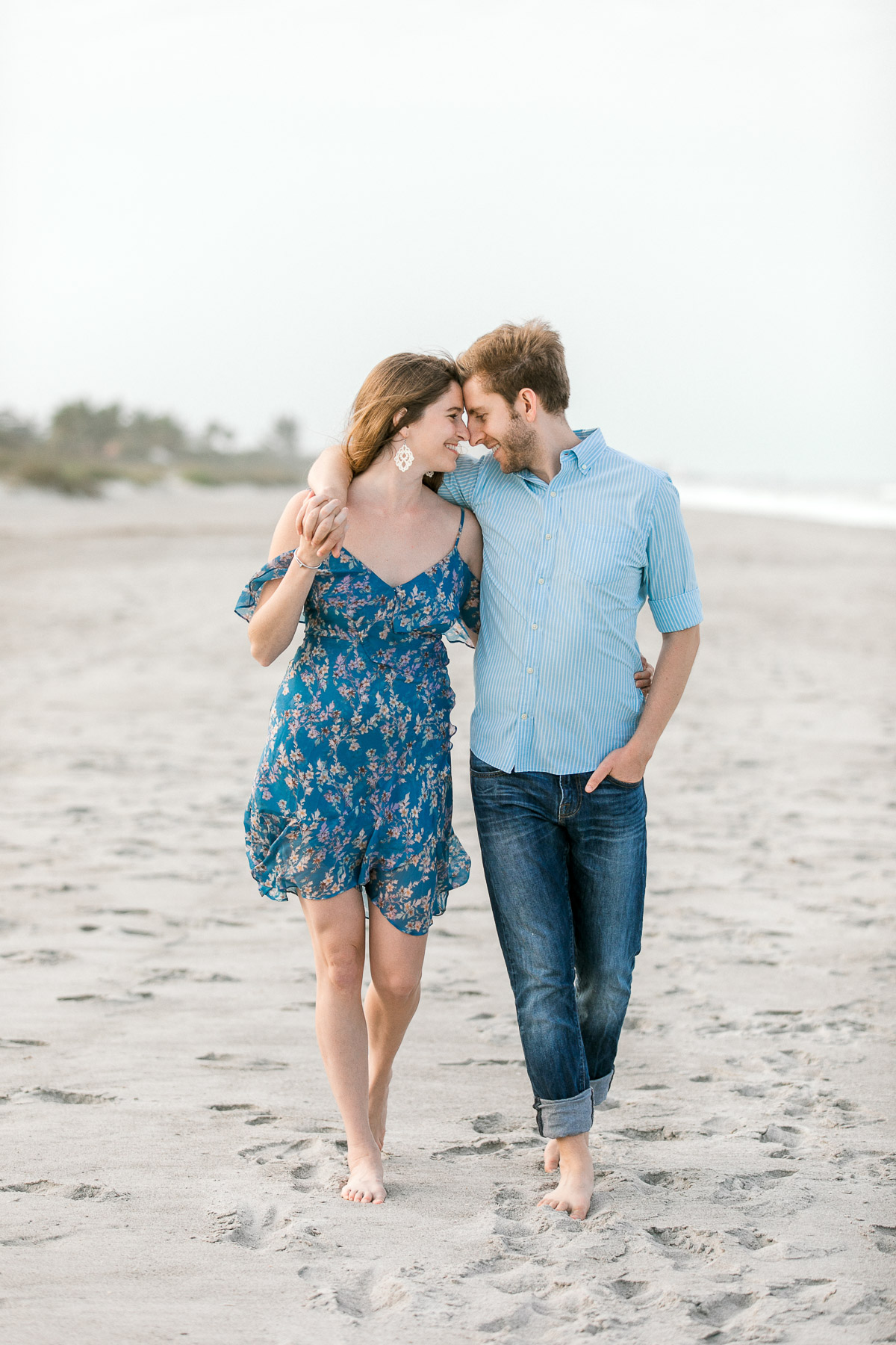 Couple walking along the beach while hugging and looking at each other