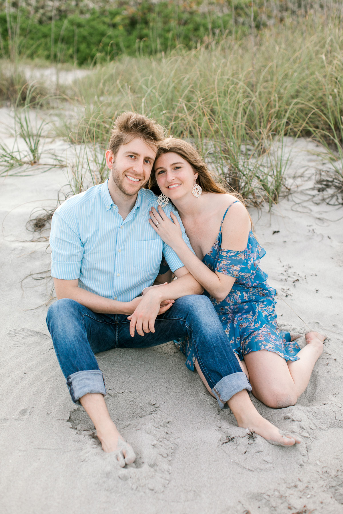 Couple sitting on the sand and smiling at the camera