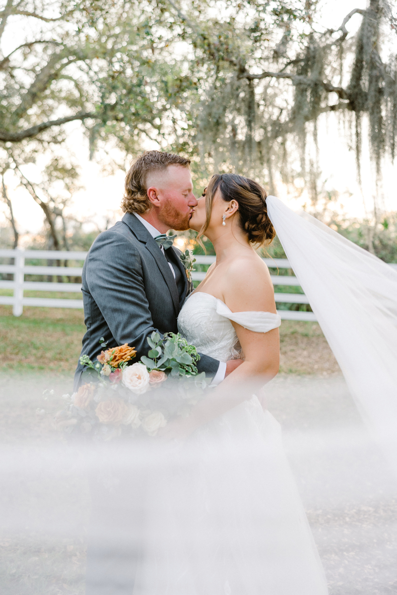 bride and groom kissing wrapped in veil